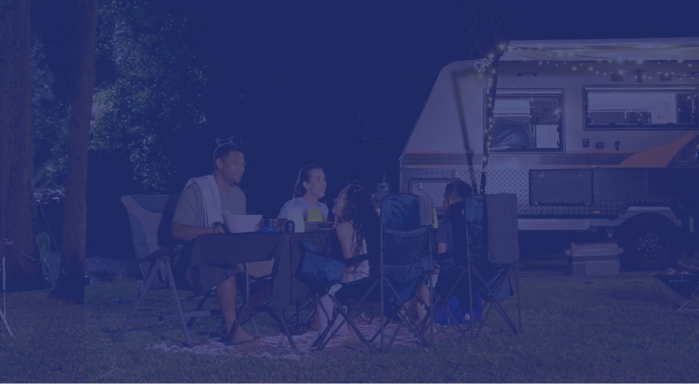 Background image of a family enjoying a meal around a campsite