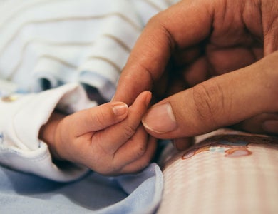 Adult hand holding tiny baby hand